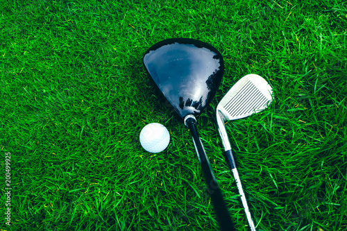 Golf sticks and a ball on a green grass background, macro view, luxury sport play game lifestyle concept.