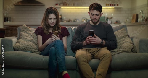 Couple at home using their smartphones.