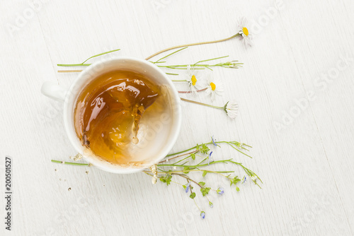 cup of splashing herbal tea on white table
