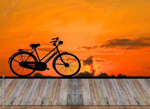 Empty top wooden table on sunrise and vintage bike background.