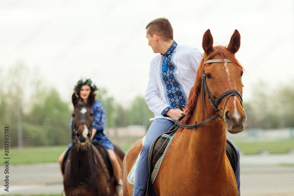 Obraz premium The guy rides on a horse and looks at his girlfriend who rides a horse behind him