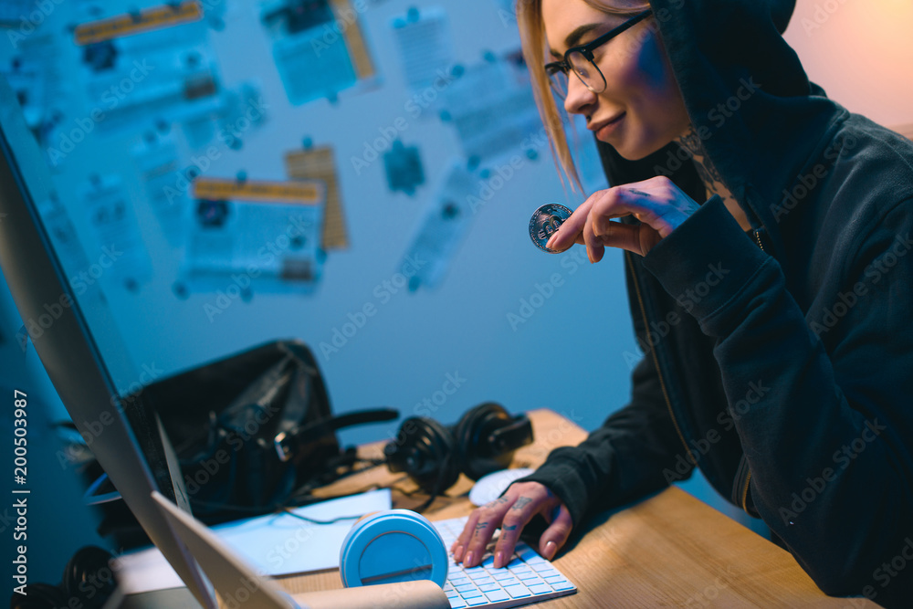 side view of young female hacker holding bitcoin side view of young female hacker holding bitcoin