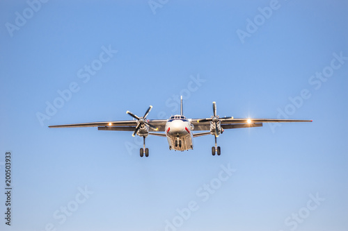 white airplane with screw engines with chassis released in the blue sky, front view