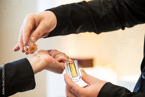 Close Up Shot Of A Sales Man's Hand Trying And Testing The Aromatic Oud Oil  On A Woman's Wrist And Holding The Jar Bottle On Other Hand