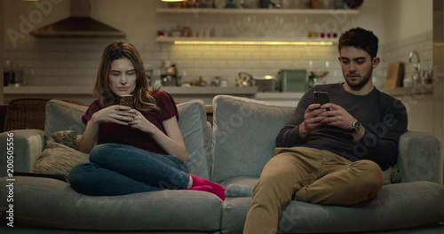 Married couple sitting on a sofa using their smart phones