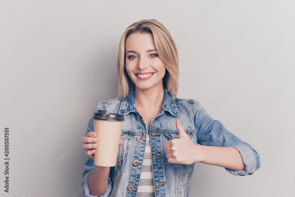 Portrait of pretty, lovely, sweet, modern, stylish girl having mug of tea in hand, gesture thumb up symbol, wearing jeans shirt, looking at camera, isolated on grey background - obrazy, fototapety, plakaty 