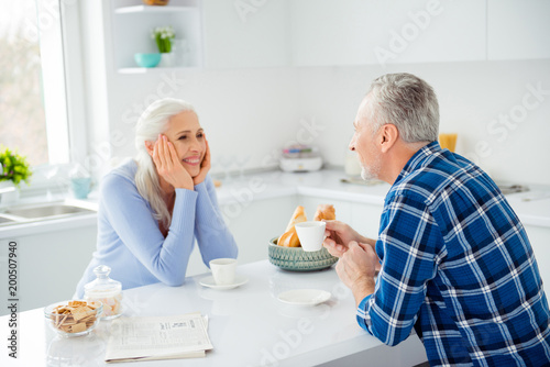 Portrait of charming attractive sweet cute lovely woman sitting in front of her lover at the table in kitchen, having mug with tea looking to each other, spending nice time together