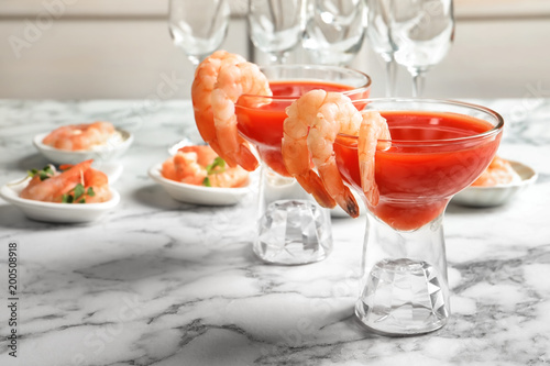 Glasses with boiled shrimps and tomato sauce on table