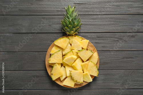 Plate with fresh sliced pineapple on wooden background