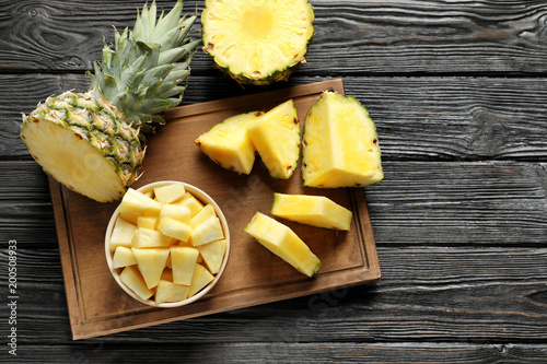 Wooden board with fresh sliced pineapple on table, top view