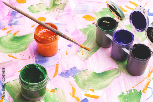 Fototapeta Naklejka Na Ścianę i Meble -  on the painted paper there are banks with paints for creativity, a brush for drawing on orange paint