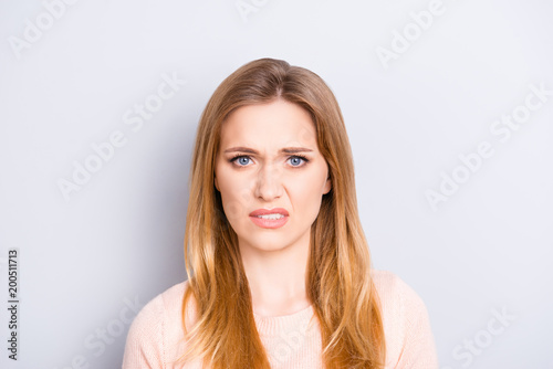 Close up portrait of funny confused puzzled unhappy upset sad uncertain unsure beautiful pretty charming grimacing woman with long blonde hairdo isolated on gray background opy-space