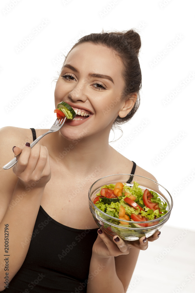 Young beautiful woman eating salad on white background Young beautiful woman eating salad on white background