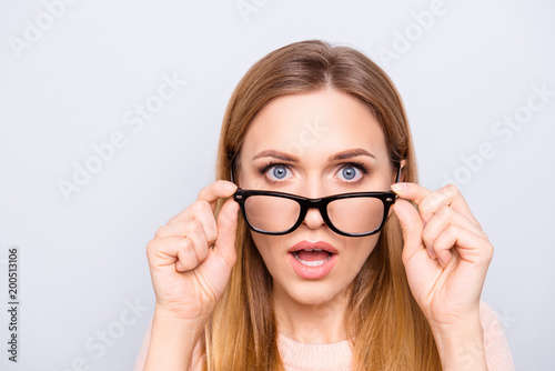 Close up portrait of pretty clever smart intelligent beautiful shocked charming lady with long straight hairstyle correcting fixing glasses looking staring with open mouth isolated on gray background