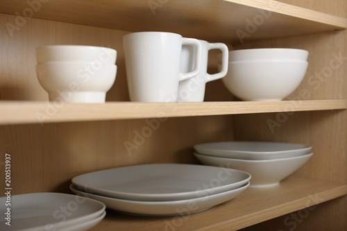Different white dishes in cupboard in the kitchen. Scandinavian style.