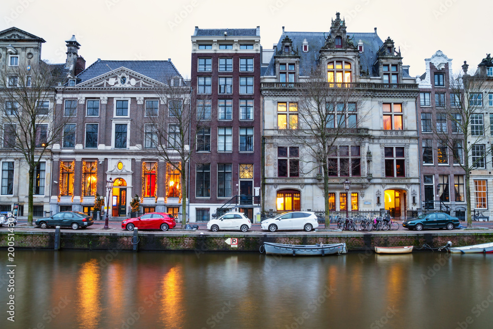 Cityscape - evening view of the houses with festive decorations and the city channel with boats, city of Amsterdam, The Netherlands