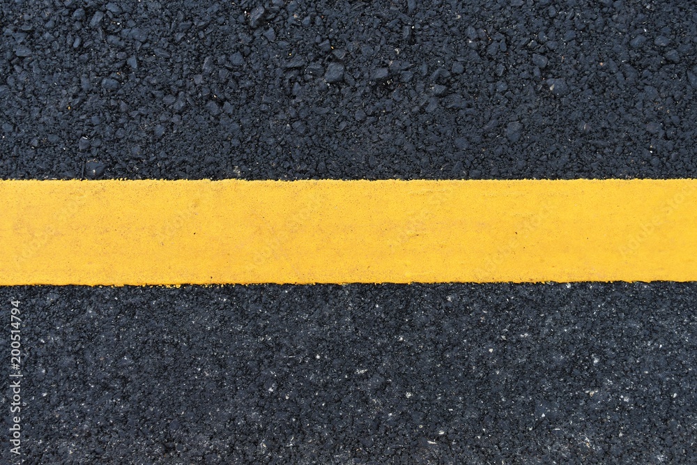 Fototapeta premium dirty orange line on surface of old asphalt in countryside
