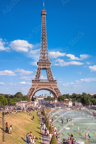 A beautiful view on the Eiffel Tower and people who splash in the fountain on a hot summer day, the city of Paris, France