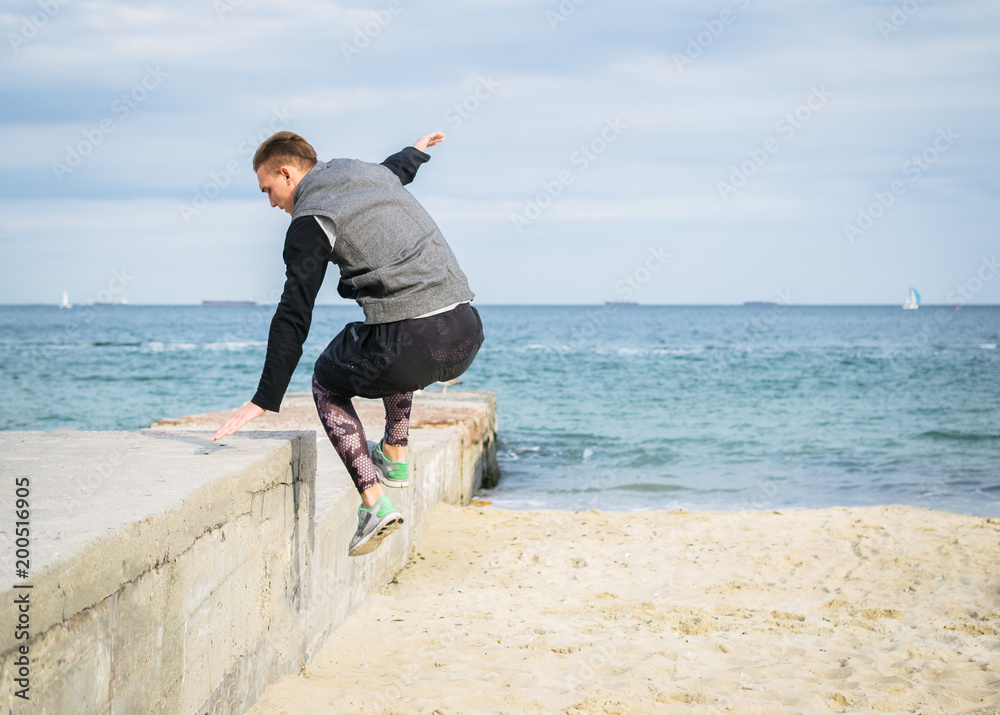 Young man doing parkour tricks on the beach near the sea Young man doing parkour tricks on the beach near the sea