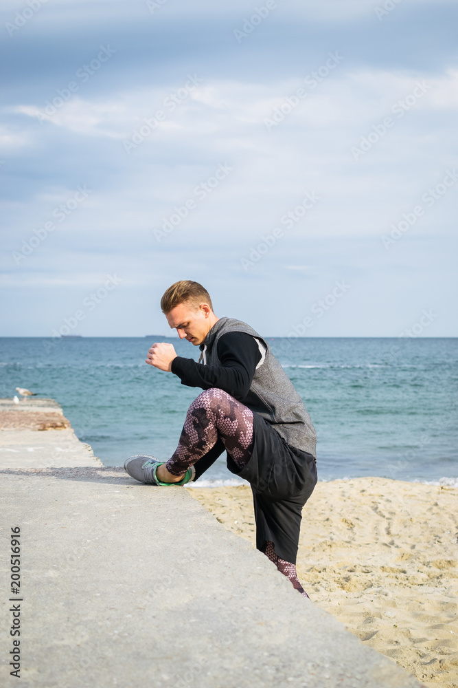 Young man doing parkour tricks on the beach near the sea Young man doing parkour tricks on the beach near the sea