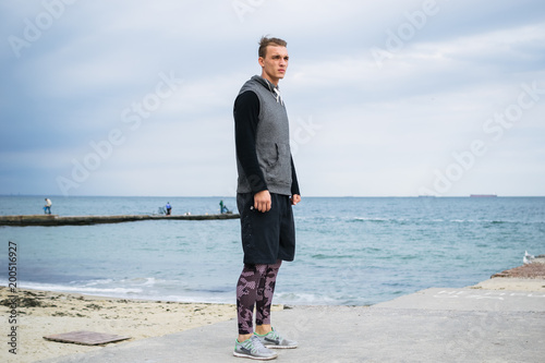 Young man doing parkour tricks on the beach near the sea photo