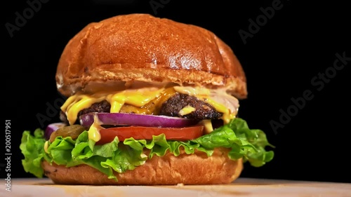 Cool beautiful fresh juicy cooked burger rotate on turntable. Very luscious air bun and marbled beef. Restaurant where each burgers is cooked by hand. Not made ideal. Not conveyor. Looks real, loving