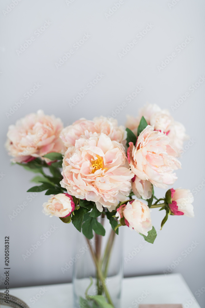 A bouquet of decorative peonies stands on a gray background. Vertical photo