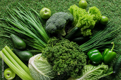 top view of uncooked tasty green vegetables on grass, healthy eating concept photo
