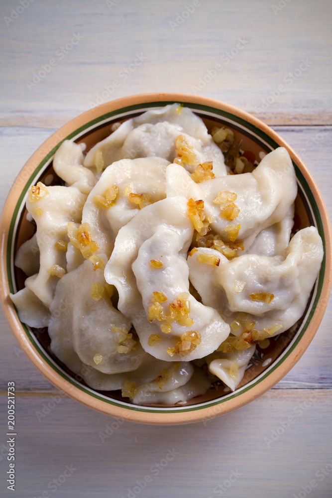 Pierogi or pyrohy, varenyky, vareniki, dumplings in bowl on wooden table. vertical Pierogi or pyrohy, varenyky, vareniki, dumplings in bowl on wooden table. vertical
