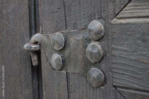Real wooden texture with a hand-wrought iron element. Wood with iron background. A wooden door with an iron lock of old times. Old retro wooden door with vintage iron locker.