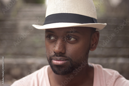 Portrait of a young black bearded man with a white hat