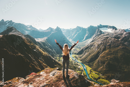 Woman traveler raised arms standing alone on cliff in mountains landscape Travel healthy Lifestyle adventure active vacations getaway in Norway