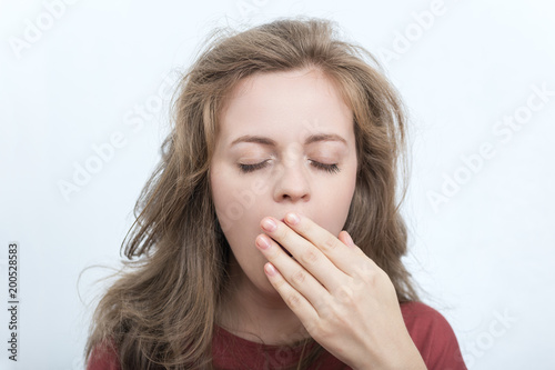 Young sleepy caucasian woman with messy hair yawning 