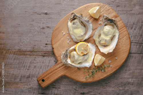 Opened oysters and lemon on wooden board.