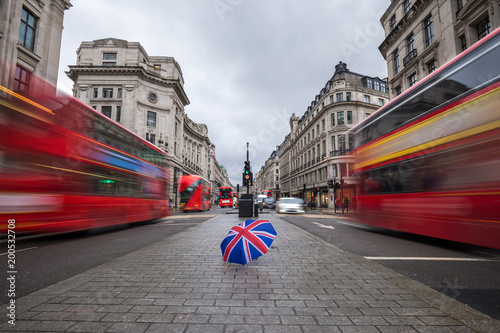 Платно London, England - British umbrella at busy Regent Street with iconic red double-
