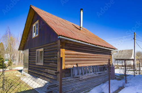 Typical Russian dacha made from wooden logs with chimney at blue sky background photo