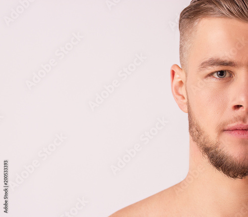 Close up of handsome man's half face isolated over white background. Portrait of attractive bearded hipster standing against white background. Masculinity and charisma and male beauty concepts