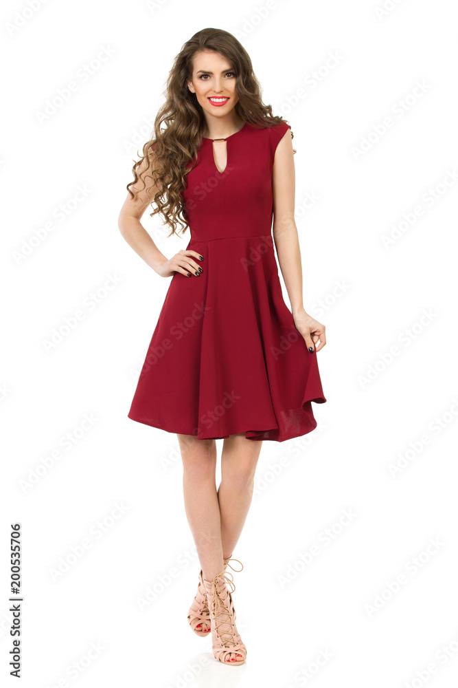 Young Woman In Elegant Burgundy Dress Is Walking With Hand On Hip