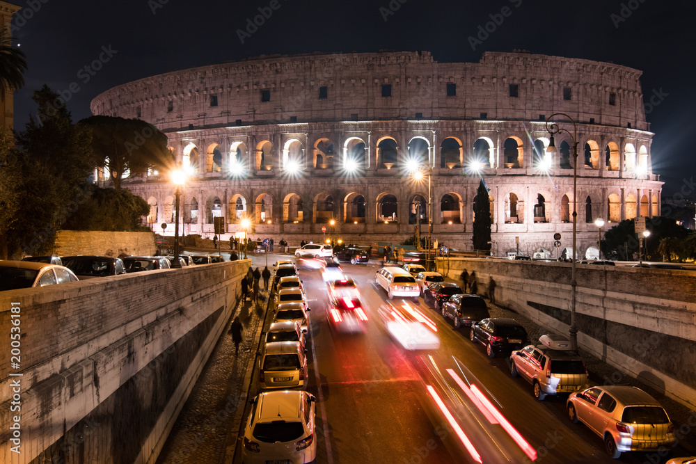 Traffic passes under a bridge leading up to the Colosseum in Rome