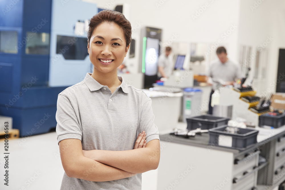 Portrait Of Female Engineer On Factory Floor Of Busy Workshop Portrait Of Female Engineer On Factory Floor Of Busy Workshop