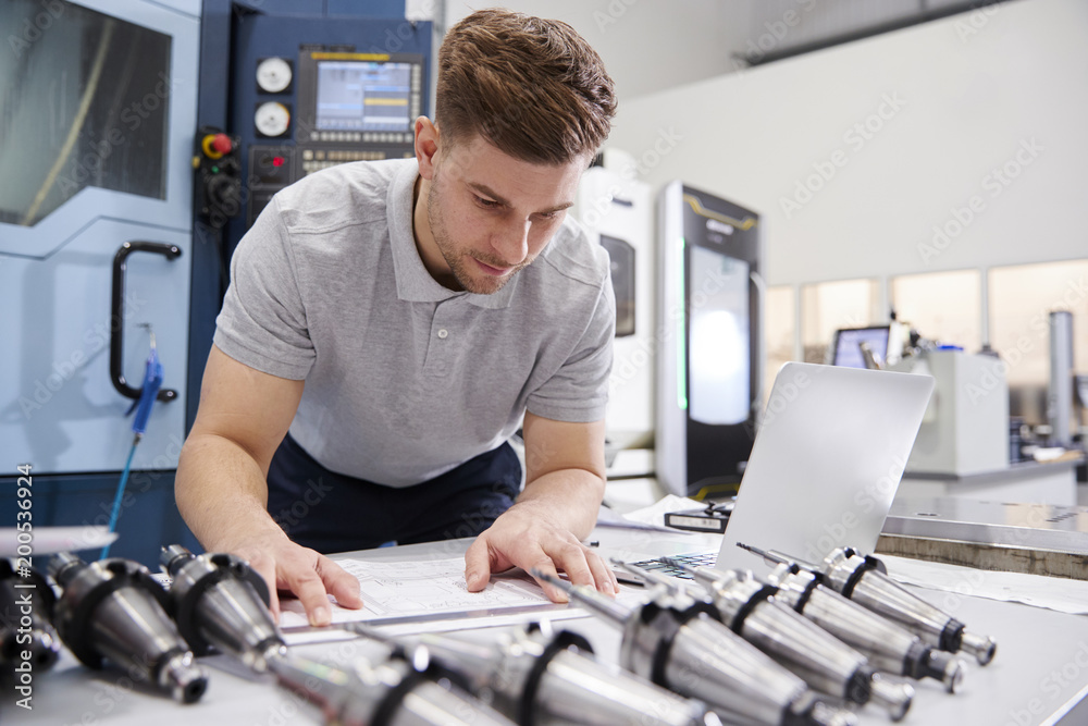 Male Engineer Measuring CAD Drawings In Factory Male Engineer Measuring CAD Drawings In Factory