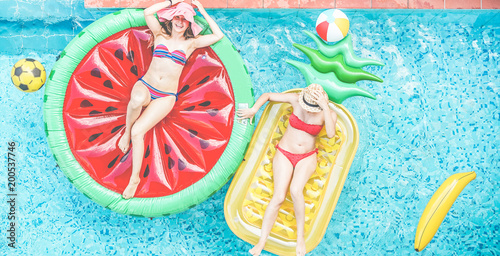 Happy girls floating with tropical fruit lilos inside swimming pool photo