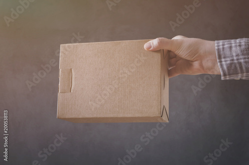 Man`s hand with carton box on dark background. photo