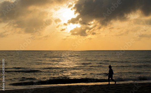 People walking on the beach at sunrise happily and the skies are a beautiful light © pcbang