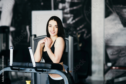 Beautiful sexy woman with a sports body in black and white sportswear trains in the gym