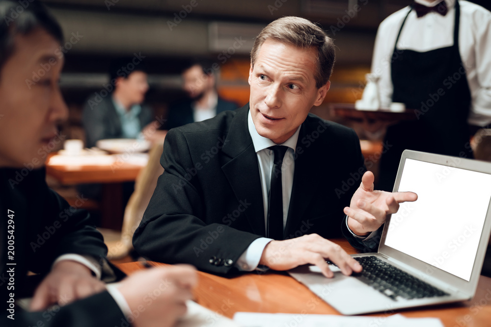Meeting with chinese businessmen in restaurant. Men are looking at laptop. Meeting with chinese businessmen in restaurant. Men are looking at laptop.