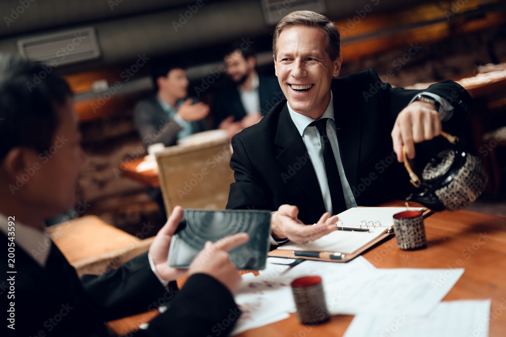 Meeting with chinese businessmen in restaurant. One man is pouring tea. Meeting with chinese businessmen in restaurant. One man is pouring tea.