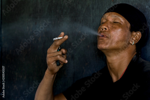 A man is smoking cigarette on black background