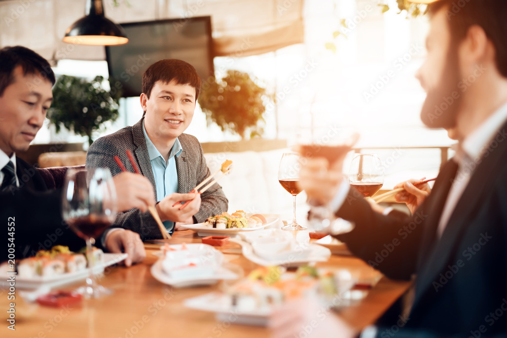 Meeting with chinese businessmen in restaurant. Men are eating sushi. Meeting with chinese businessmen in restaurant. Men are eating sushi.