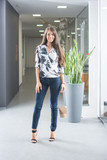 Full length portrait of young business woman standing in office hall.